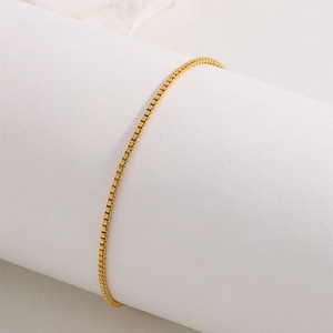 Gros plan d'un bracelet en acier inoxydable doré avec pendentif feuille et chaîne box