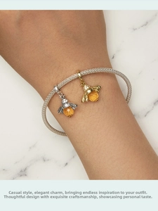 Macro shot of silver mesh bracelet with golden and silver crystal bee charms on wrist