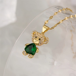 Macro detail of gold teddy bear pendant with green gemstone and micro-pave zircons