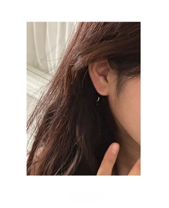 Dettaglio di orecchini a fiocco in argento 925 con design a croce su modella femminile