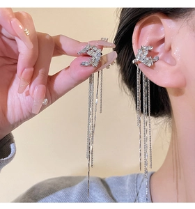 Macro detail of silver bow tassel earrings featuring sparkling rhinestones on long chains