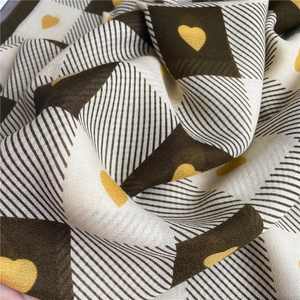 Close-up of soft diagonal checkered scarf with yellow heart patterns and draping texture