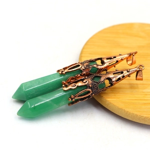 Detail of green hexagonal crystal pendants with vintage copper caps on a wooden tray