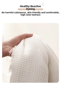 Close-up of white waffle weave fabric with tassels showing soft texture and thickness