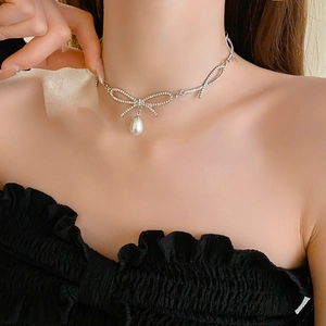 Gros plan d'un collier nœud argenté avec pendentif perle porté par un mannequin