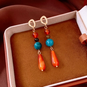 Detailed macro of beaded drop earrings with colorful agate stones and gold metal accents