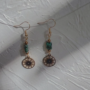 Detail of 18K gold stainless steel earrings with green natural stone and sunburst pendant
