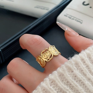 Detailaufnahme des goldenen asymmetrischen Rosenrings am Finger mit Vintage-Relieftextur