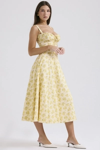 Detail of elegant yellow floral strap dress showing the light fabric and side drape