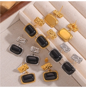 Detail of vintage textured square earrings with black glass inlay and gold finish