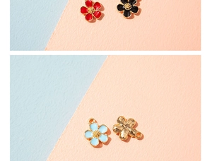 Detail of four colorful enamel flower charms in red, blue, black and gold for DIY jewelry