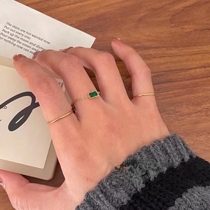 Detail of adjustable gold chain ring with green zircon and minimalist stackable bands