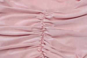 Dettaglio ravvicinato della trama in tessuto increspato rosa e cuciture dell'abito