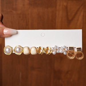 Close-up of 6-pair gold earring set with faux pearls and enamel on white display card