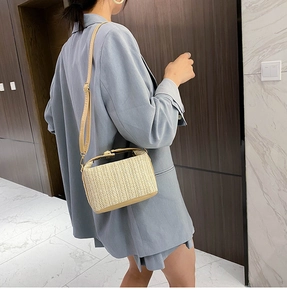 Detail of hand-woven straw crossbody bag with V-pattern texture and PU leather strap