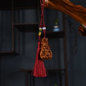 Macro shot of carved wood deity pendant with red tassel on natural branch background