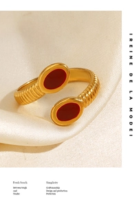 Detail shot of vintage gold-plated open ring with red drip oil oval accents on white silk