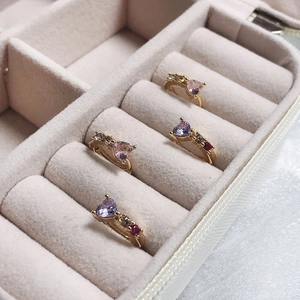Détails de quatre boucles d'oreilles cœur en zircon doré sur velours rose doux