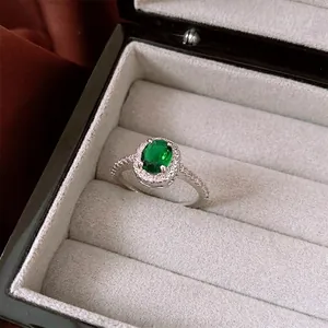 Elegant oval green zircon ring with halo setting on luxury gray velvet jewelry box