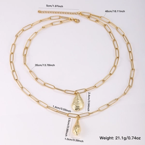 Layered gold necklace featuring two conch and shell pendants on a white background
