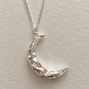 Macro shot of 925 silver crescent moon necklace with artistic hammered metal texture