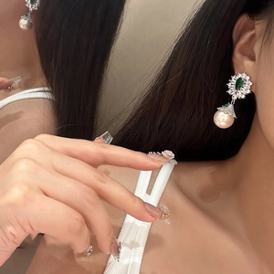 Macro detail of emerald green zircon drop earrings with large round pearls and diamonds