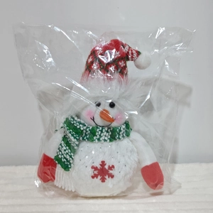 Close-up of a Christmas snowman plush toy with festive hat and scarf in clear packaging