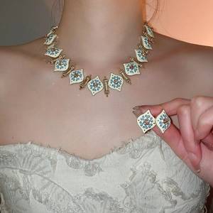Vintage style gold floral jewelry set with white enamel necklace and matching earrings