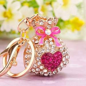 Close-up of rhinestone heart slipper keychain with rose pink bow on golden metal finish