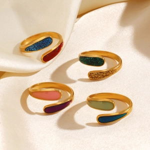 Set di quattro anelli geometrici in acciaio dorato con smalto colorato su seta bianca