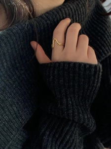 Minimalist wavy 925 silver ring in gold worn on index finger with knit sweater background