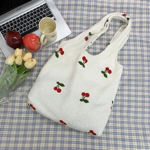 Close-up of white fleece tote bag featuring detailed red cherry embroidery and soft texture