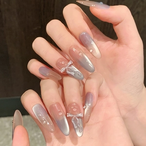 Close-up of almond-shaped cat eye press-on nails with 3D bows and water drop charms