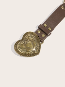 Close-up of vintage gold heart buckle with floral carvings on a brown leather belt