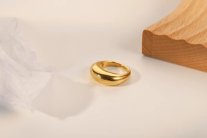 Nahaufnahme eines dicken minimalistischen 18k vergoldeten Rings mit polierter Wölbung