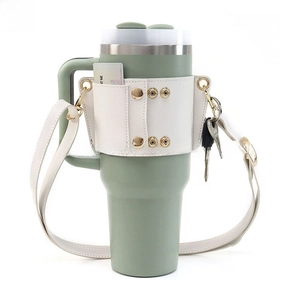 Close-up of sage green cup with cream leather sleeve featuring card pocket and key hook