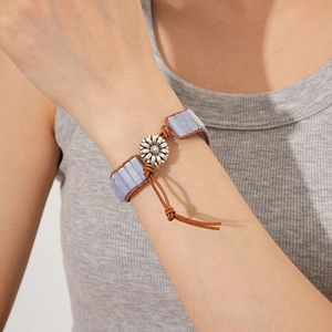 Dettaglio di un bracciale boho in pelle con pietra azzurra e chiusura a girasole