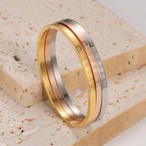 Three-piece stackable bangle set in gold, rose gold, and silver with grid pattern engraving