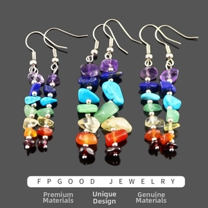 Macro shot of seven chakra natural crystal stone earrings on a dark reflective surface