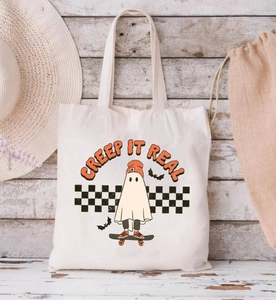 Detailed close-up of a white canvas tote bag with a cute Halloween ghost on skateboard print