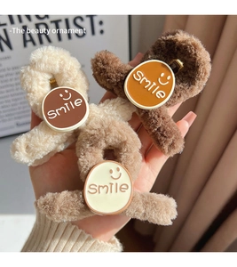 Detailed view of three plush hair claws in cream, light brown, and dark brown with smile patch