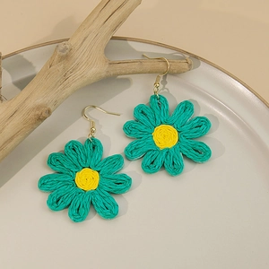 Gros plan détaillé des boucles d'oreilles marguerites tissées en vert et jaune