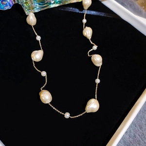 Close-up of baroque pearl necklace with gold plated chain on black velvet background