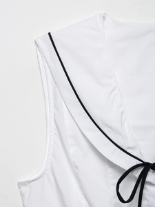 Detail of white sleeveless top with contrast black trim and navy collar bow tie