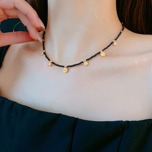 Gros plan d'un collier ethnique avec perles noires et pendentifs ronds en métal doré