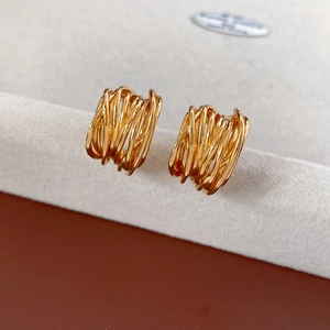 Close-up of gold plated multi-layer entwined C-shaped earrings with a polished finish