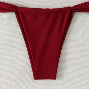 Detail of burgundy high-cut bikini bottoms with decorative side knot and elastic fabric