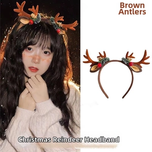 Close-up of brown plush reindeer antlers headband with pine needles and red berry details