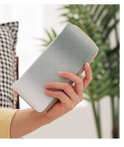 Handheld view of light blue quilted PU leather clutch wallet with gold zipper detail