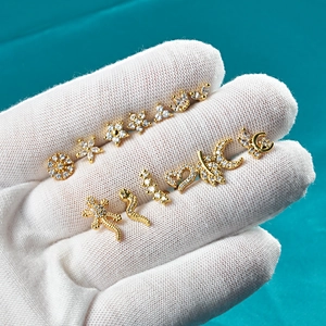 Macro detail of gold-plated stainless steel stud earrings set on a white glove